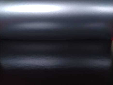 Gradient on a gray-black background. Horizontally folded shiny paper or foil with overflow and highlights. Mysterious radiance. Luxurious fabric. Metallic cold shine