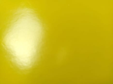 Beautiful bright yellow background. Close-up sheet of shiny reflective incident light paper. Pure fun color. Intense shade of yellow, close to gold or sunny with high reflectivity.