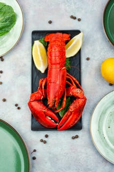 Boiled lobster with greens and lemon on a plate. Seafood.