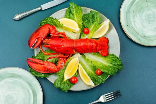 Boiled lobster with lettuce and lemon on a plate. Seafood, copy space