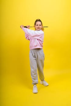 Full length studio photo of ten year old girl holding a badminton racket and isolated on yellow.