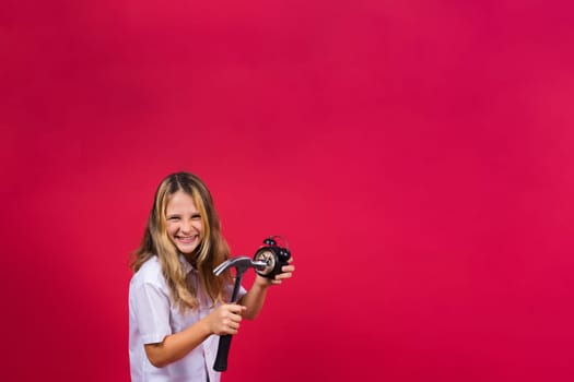 Kid girl holding hammer and alarm clock smiling with happy and cool smile on face. showing teeth.