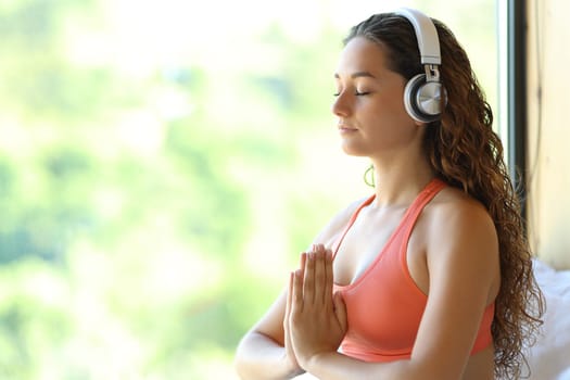 Happy woman meditating with headphone at home