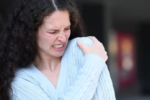 Woman suffering shoulder ache complaining in the street