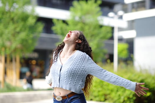 Excited woman in the street outstretching arms screaming