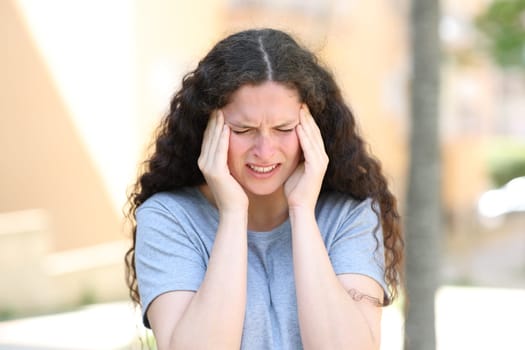 Woman suffering migraine complaining in the street