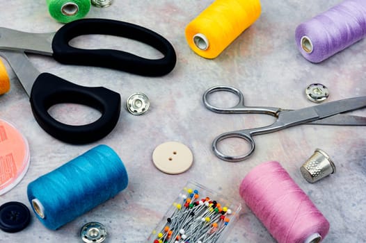 Home sewing kit, scissors, color threads, needles and buttons. Needlework concept