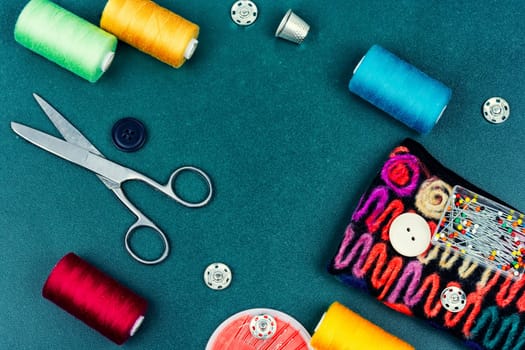 Home sewing kit, scissors, color threads, needles and buttons. Needlework concept