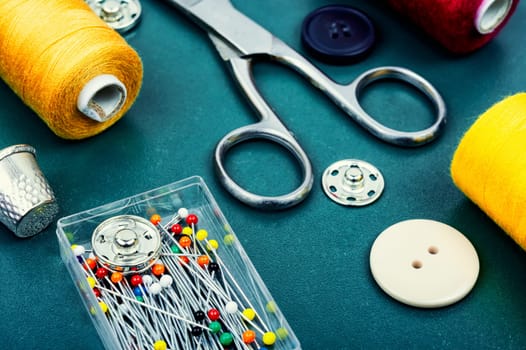 Home sewing kit, scissors, color threads, needles and buttons. Needlework concept