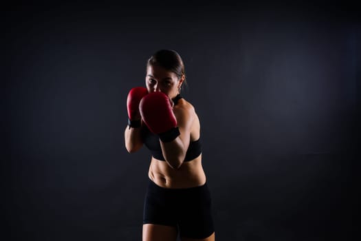 Cool female fighter in boxing bandages trains in a studio. Mixed martial arts.