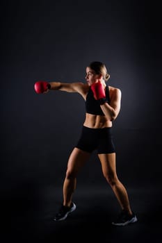 Cool female fighter in boxing bandages trains in a studio. Mixed martial arts.
