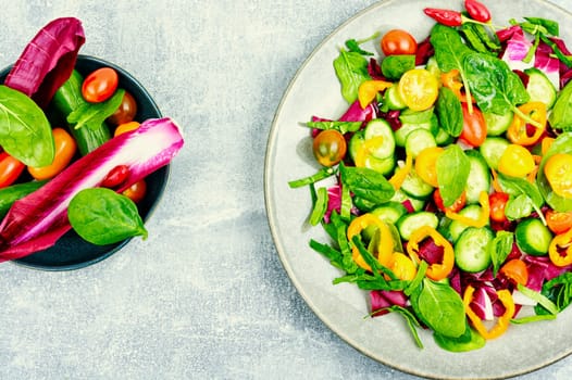 Summer natural salad of tomatoes, cucumbers, peppers and spinach. Vegetarian food
