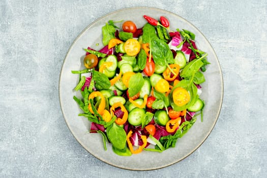 Summer natural salad of tomatoes, cucumbers, peppers and spinach.
