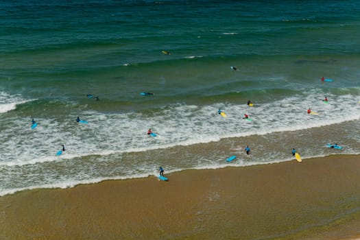 View of surfers on sandy beach near Sagres village in Algarve, Portugal