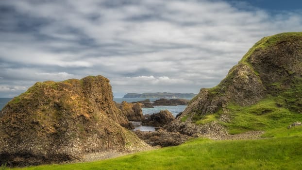 Beautiful coastline with hills, cliffs and small rocky islands on Causeway Coast at Ballintoy Harbour, County Antrim, Northern Ireland
