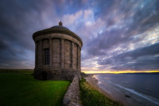 Small Mussenden Temple on the edge of a cliff with dramatic, moody sunset, National Trust, Castlerock, County Antrim, Northern Ireland