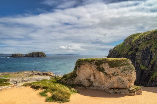 Whit rocks, cliffs and sandy beach at Ballintoy Harbour on Causeway Coast, County Antrim, Northern Ireland