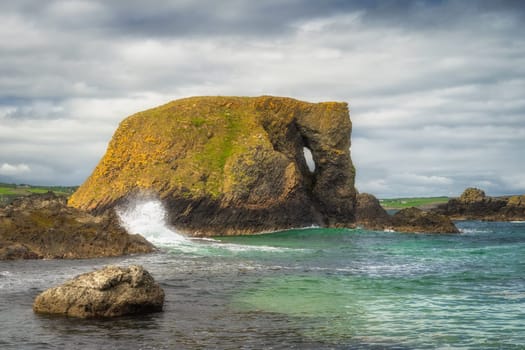 Beautiful costal rock formation, Elephant Rock with splashing wave and turquoise water on a Wild Atlantic Way in Country Antrim, Northern Ireland