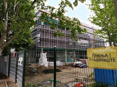 Sremska Mitrovica, Serbia. May 30, 2020. Construction of a new school in Sremska Mitrovica. The building is in the final stages of construction. Facade work. Metal fencing. The inscription in Serbian is: Caution, Construction.