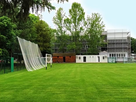 Sremska Mitrovica, Serbia. May 30, 2020. A football field on the school grounds and a football goal. The construction of a new school. School building in scaffolding. Facade work at the final stage of construction