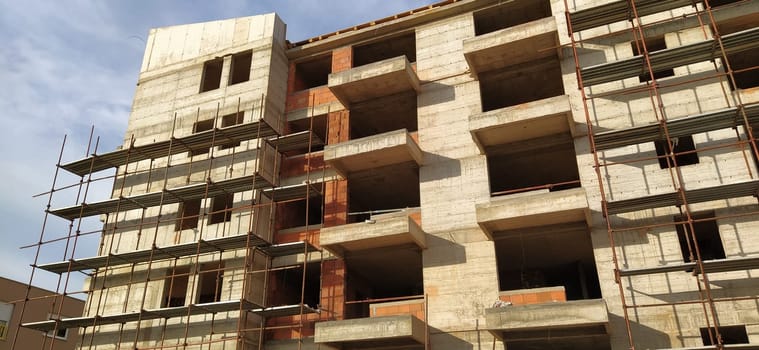 Construction of a quarter of five-story houses made of monolithic concrete. Industry, construction, real estate. Building facade, scaffolding. New construction technologies for earthquake-prone areas