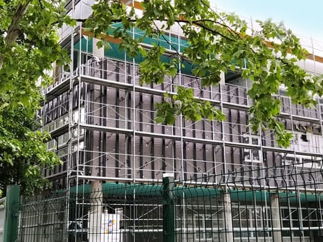 Sremska Mitrovica, Serbia, May 30, 2020. Construction of a new school building. Scaffolding on the facade. Metal fence. Finishing work.