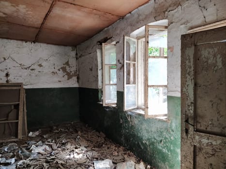 Scary windows. Inside an abandoned house. View of broken windows without a curtain. Grunge scene. Light shines through old wooden frames with broken glass. The concept of abandonment and uselessness