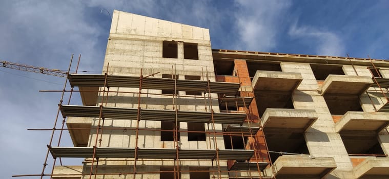 Construction of a quarter of five-story houses made of monolithic concrete. Industry, construction, real estate. Building facade, scaffolding. New construction technologies for earthquake-prone areas