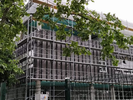 Sremska Mitrovica, Serbia, May 30, 2020. Construction of a new school building. Scaffolding on the facade. Metal fence. Finishing work.