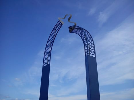 Metallic blue designs crowned with gold curls. In the background is the sky.