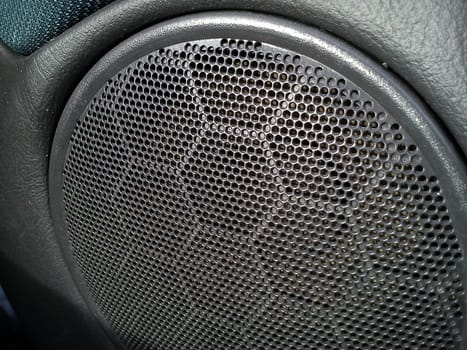 Gray grill from a music speaker in a car. The interior of the car. Acoustic stereo speakers. Radio in the form of toys or with a stylish design.