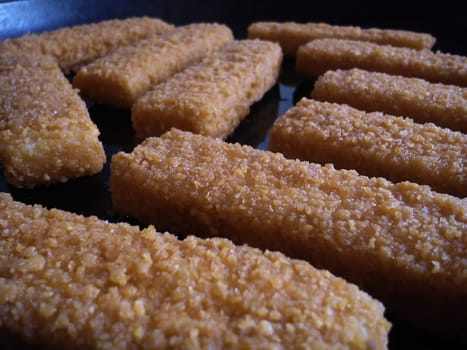 Fish or crab sticks are fried in a cast iron skillet in vegetable oil Fast food, which became carcinogenic after frying. Diet products and fish menu in the restaurant.
