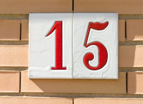 House number 15 over brick sunny wall. Houses with personality concept