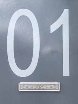 House number 01 over grey metal surface. Houses with personality concept