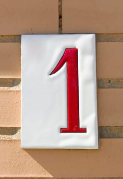 House number 1 over brick sunny wall. Houses with personality concept