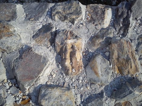 Stones connected by cement mortar. Archaeological excavations of the walls of ancient Roman buildings in Sremska Mitrovica, Serbia. Restored collapsing walls. Small pebbles, sand, autumn leaves, dust.