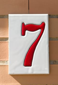 House number 7 over brick sunny wall. Houses with personality concept