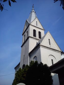 Ruthenian church in the city of Sremska Mitrovica, Serbia. The upper part of the building, the dome and the bell tower. Venetian blinds on high windows and a cross instead of a spire. Clear blue sky.