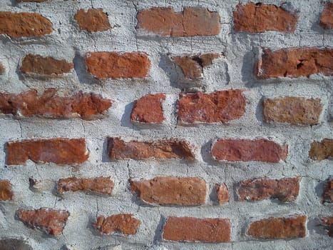 Old roman brick. The restored wall of the building of Roman times. Morning sunlight and warm brown-red shades of uneven bricks. Archaeological site in Serbia, central square of Sremska Mitrovica.