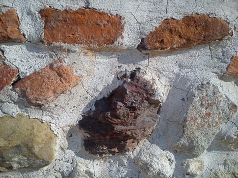The restored wall of the building of Roman times. Sunlight accentuates the warm brown-red shades of uneven bricks. In addition to red bricks, stones of indefinite shape were also used