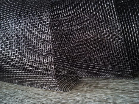 Mosquito net in a roll. Brown synthetic material on a white background. Weaving plastic threads. Convoluted lattice
