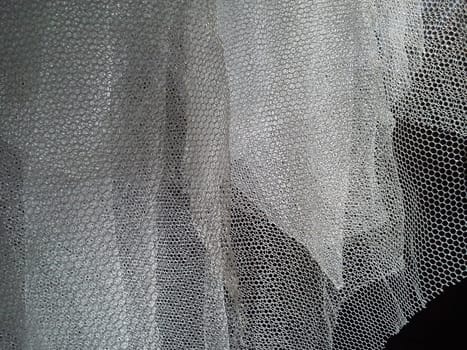 White wrinkled mesh fabric. A washable thing made of synthetic material. Mosquito net folded into soft folds. Fabric similar to a bridal veil.