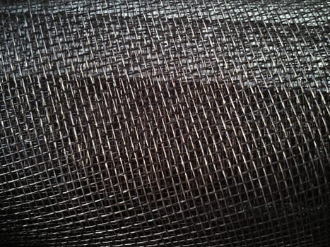 Mosquito net in a roll. Brown synthetic material on a white background. Weaving plastic threads. Convoluted lattice