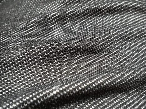 A textile fabric made on a loom by weaving mutually perpendicular thread systems. Black and white synthetic polyester fabric for sewing clothes, upholstery, and other products. Material close-up.