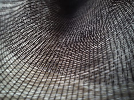 Mosquito net in a roll. Brown synthetic material on a white background. Weaving plastic threads. Convoluted lattice