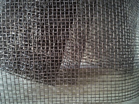 Mosquito net in a roll. Brown synthetic material on a white background. Weaving plastic threads. Convoluted lattice