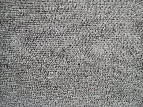 Fragment of a dense thick gray fabric. Fine weaving of threads creates an uneven texture. The surface is rough, but soft to the touch.