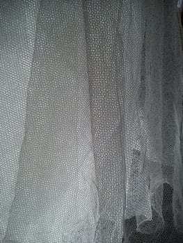 White wrinkled mesh fabric. A washable thing made of synthetic material. Mosquito net folded into soft folds. Fabric similar to a bridal veil.