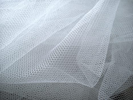 White wrinkled mesh fabric. A washable thing made of synthetic material. Mosquito net folded into soft folds. Fabric similar to a bridal veil.