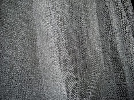 White wrinkled mesh fabric. A washable thing made of synthetic material. Mosquito net folded into soft folds. Fabric similar to a bridal veil.